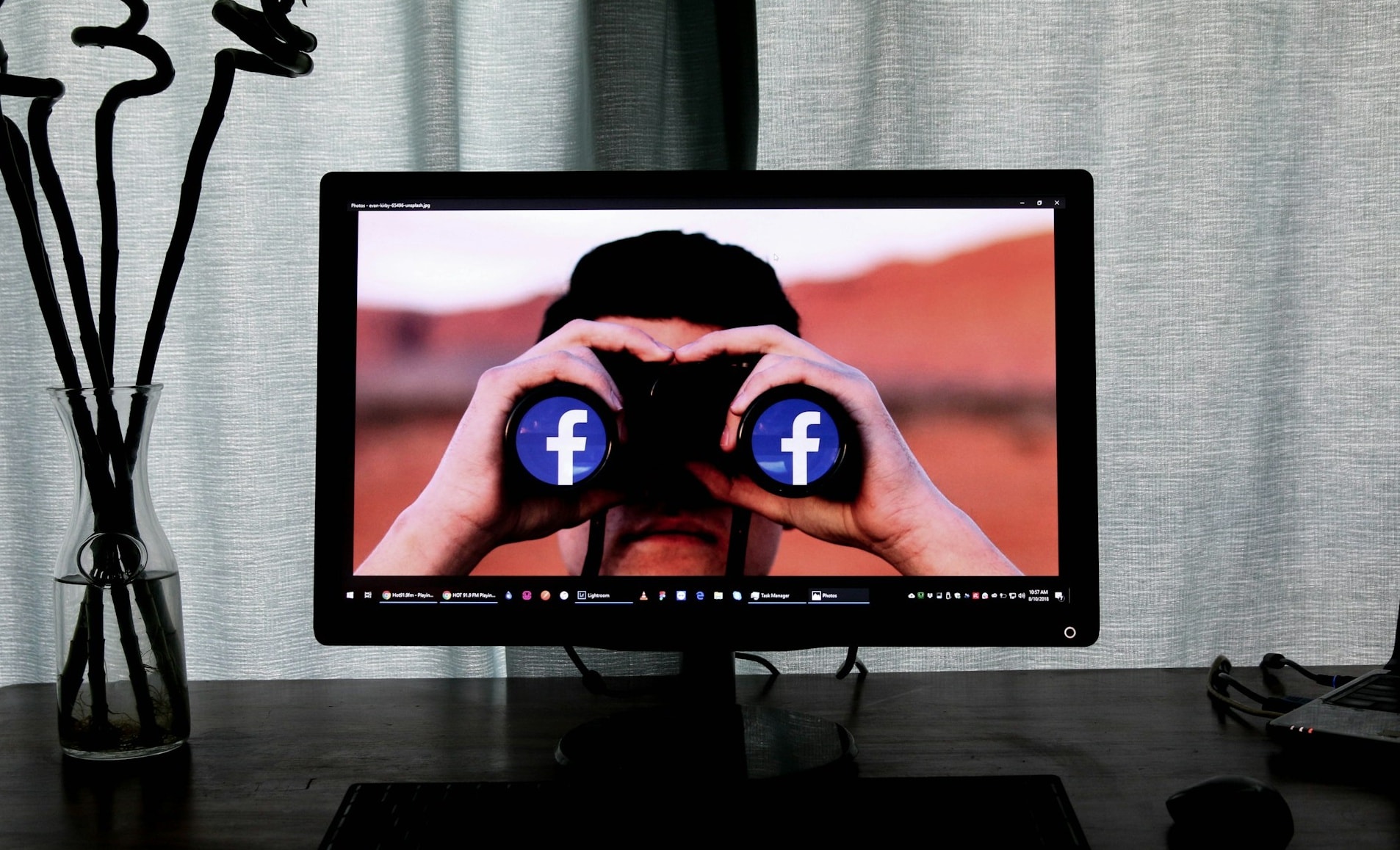 A computer monitor showing someone using binoculars with the Facebook logo on each lens