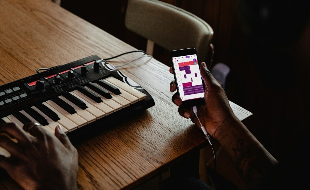 Person playing a MIDI keyboard and using a mobile recording studio app